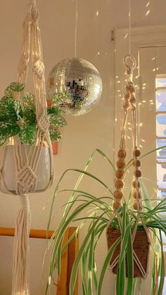 three hanging planters with plants in them and some disco ball decorations on the wall