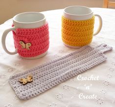 two crocheted coffee mugs sitting on top of a table