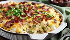 a casserole dish with bacon, green onions and cheese in it on a table