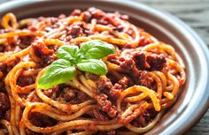 a bowl filled with spaghetti and sauce on top of a wooden table