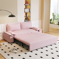 a pink couch sitting on top of a white rug next to a book shelf filled with books