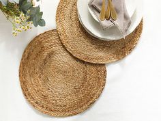 two placemats and one plate on a white table with flowers in the background