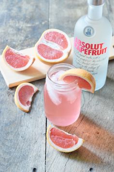 grapefruit and gin on a wooden table next to a bottle