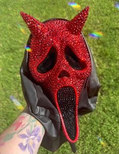 a person wearing a red devil mask on their hand