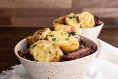 two white bowls filled with potatoes and meat