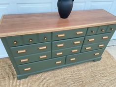 a green dresser with gold handles and drawers