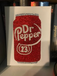 a red and white can with the word dr pepper on it sitting next to some books