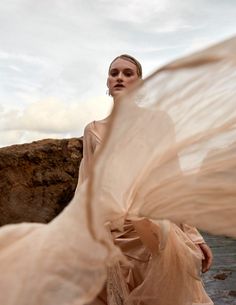 a woman in a flowing dress on the beach