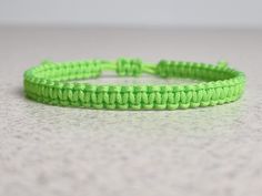 a close up of a neon green bracelet on a table with a white wall in the background