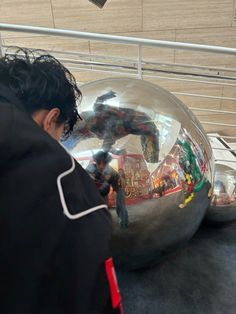 a person standing next to a large metal ball