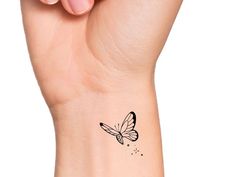 a woman's wrist with a small butterfly tattoo on the left side of her arm