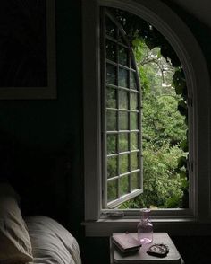 an open window in a dark room with a table next to it and a book on the side