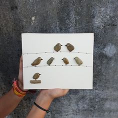 a person holding up a piece of paper with birds on it and string attached to it