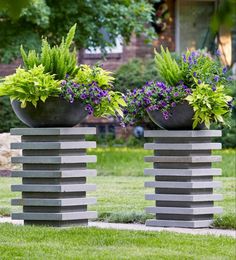 three cement planters with plants in them sitting on the grass next to each other