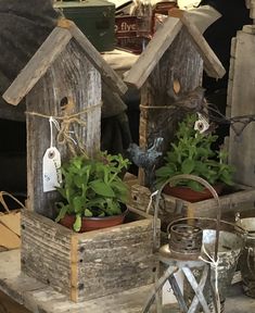 two wooden birdhouses with plants in them on a table next to other items and decorations