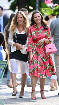 two women walking down the street with one carrying a pink purse and another holding a pink handbag