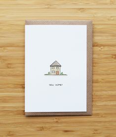 a card with a house drawn on it sitting on top of a wooden table next to a