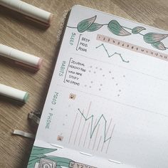 three pens are sitting on top of a notebook with an image of flowers and leaves