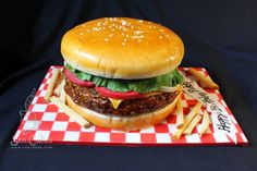 a hamburger and fries are on a red and white checkerboard tray with black background