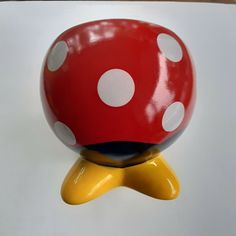 a red and white polka dot ball sitting on top of a yellow object