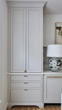 a white cabinet with two drawers and a lamp