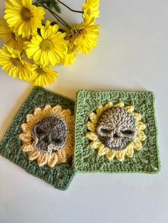 two crocheted coasters sitting next to each other with yellow flowers in the background