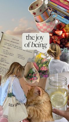 two women and a cat are sitting in front of a sign that says the joy of being