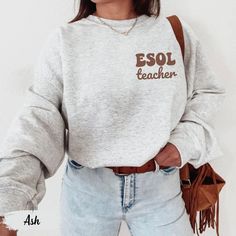 This cozy sweatshirt with "ESOL Teacher" as a pocket design is the perfect gift for multilingual educators. Ideal for ESL, ELA, and dual language teachers, it's a stylish and comfortable choice for back-to-school or any day in the classroom. Prefer this design on a T-Shirt? Visit this link: https://bohemianbloomdesigns.etsy.com/listing/1764268918 Prefer this design on a Hoodie? Visit this link: https://bohemianbloomdesigns.etsy.com/listing/1764270128 Prefer this design on a Tote Bag? Visit this Cotton Sweatshirt With Pockets For College, Basic Crew Neck Sweatshirt With Pockets, Relaxed Fit Long Sleeve T-shirt For School, Casual Relaxed Fit Sweatshirt For School, Oversized Casual Sweatshirt For School, Casual Oversized Sweatshirt For School, Oversized Cotton Sweatshirt For School, Relaxed Fit Long Sleeve Sweatshirt For School, Pre-shrunk Relaxed Fit Sweatshirt For School