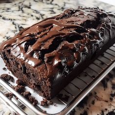 a loaf of chocolate cake sitting on top of a cooling rack