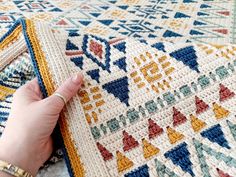 a woman is holding onto a colorful rug with her hand on the ground next to it