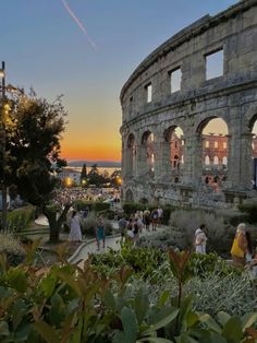 people are walking around in front of an old roman amphite at sunset or dawn