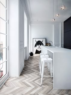 a kitchen with white walls and flooring next to a counter top, two stools in front of an open window