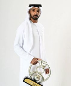 a man is holding a trophy and posing for the camera in front of a white background