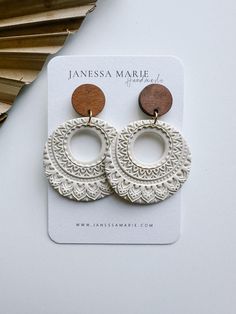 a pair of white and brown earrings sitting on top of a card