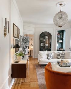 a living room filled with furniture and a chandelier hanging from the ceiling in front of a window