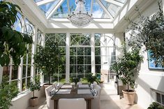 a dining room filled with lots of plants and furniture under a glass ceilinged area