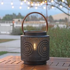 a candle holder sitting on top of a wooden table next to a tree with lights