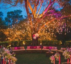 an outdoor seating area is lit up with string lights and pink pillows on the couches