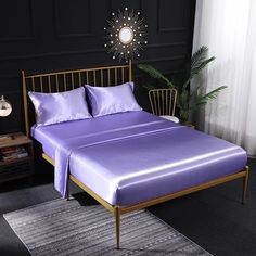 a bed with purple sheets and pillows in a room