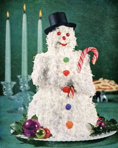 a white frosted snowman with candy canes and candies on a plate