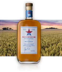 a bottle of red hot kentucky whiskey sitting on top of a field