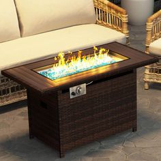 a fire pit sitting on top of a stone floor next to a white couch and wicker chair