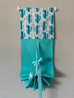 a blue and white wall hanging with a cactus print on the side, tied to a hook