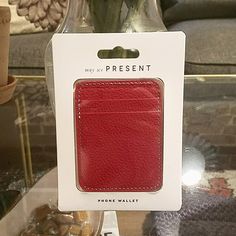 a red leather card case sitting on top of a table next to a vase with flowers