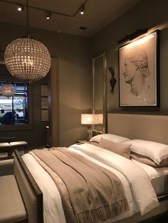 a bedroom with a large bed and chandelier hanging from it's ceiling