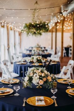 the tables are set up for an event with blue linens and gold plates on them