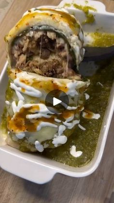 an enchilada with meat and sauce in a white dish on a wooden table