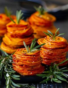 small stacks of baked sweet potatoes with rosemary sprigs on the top, ready to be eaten