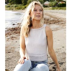 a woman sitting on the beach with her legs crossed