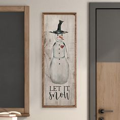 a snowman with a black hat is hanging on the wall